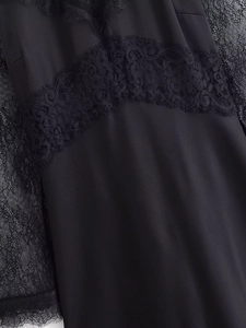 Detailed macro view of the black lace stitching and fabric texture on a long sleeve dress