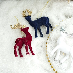 Velvet flocking Christmas reindeer ornaments with glitter antlers in snowy festive scene