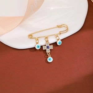 Macro shot of gold-tone cross brooch with blue evil eye pendants and rhinestone accents