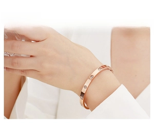 Detailed view of rose gold bangle with inlaid round zircons worn on a female wrist