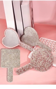 Detail of four handheld rhinestone makeup mirrors in heart, square, and round shapes