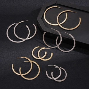 Set of gold and silver geometric hoop earrings with rhinestones on black leather background