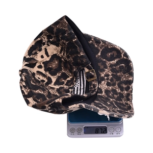 Detailed view of leopard print baseball cap on digital scale showing weight of 87.2 grams