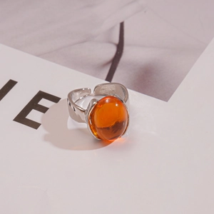 Gros plan d'une bague réglable argentée avec une pierre ovale en résine orange poli