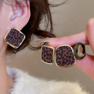 Détail de boucles d'oreilles carrées léopard avec bordure dorée portées par le modèle