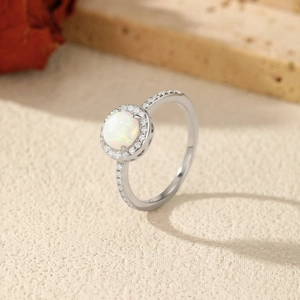 S925 sterling silver opal ring with side accents shown on a textured neutral surface