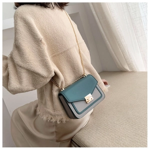 Green and grey vintage crossbody bag with gold chain strap shown on a female model