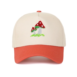 Detail of mushroom embroidery on a two-tone trucker cap with orange brim and beige crown