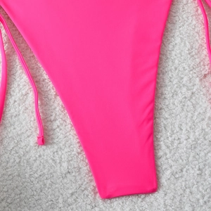 Detail of hot pink bikini bottoms with high cut leg design and adjustable side ties