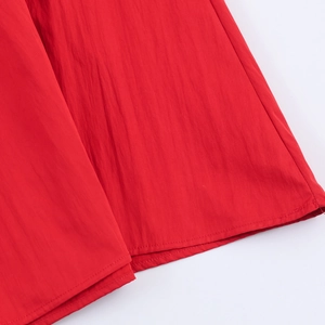 Gros plan sur la texture du tissu rouge et la couture de l'ourlet de la robe longue