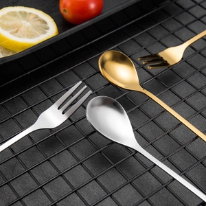 Close-up of golden and silver leaf-shaped creative dessert spoons and fruit forks on a rack