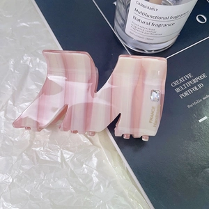 Detail of pink marble acetate hair claw clip with crystal inlay and handmade gold text