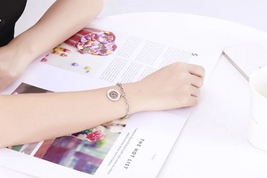 Detailed view of silver titanium steel chain bracelet with clover disc on a magazine