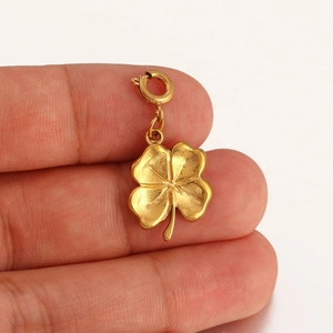 Handheld photo showing the size of a detailed 18K gold-plated four-leaf clover charm
