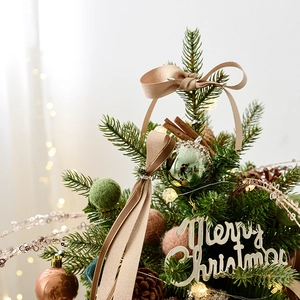 Mini Christmas tree with champagne ornaments, pine cones and warm lights on table