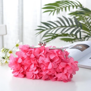 Close-up of a pink floral evening clutch bag featuring 3D petals and a silver metal clasp