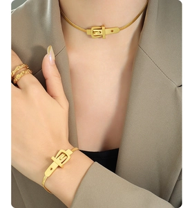 Détail d'un ensemble collier et bracelet en forme de boucle de ceinture dorée