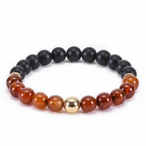 Detail of matte black onyx and red agate beaded bracelet with a central gold metal bead
