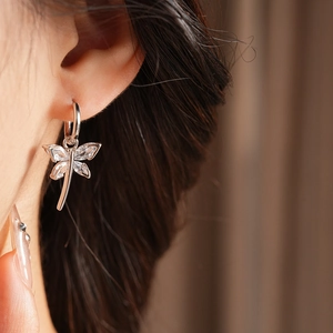 Detailaufnahme des funkelnden Libellen-Ohrrings mit Zirkon am Modellohr