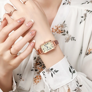 Detail of rose gold rectangular quartz watch with Milanese mesh strap on model's wrist