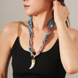 Dettaglio della collana foulard in seta con perline dorate e ciondolo a dente d'avorio