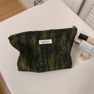 Detailed close-up of a green and black jacquard canvas pouch with a simple wish label