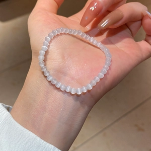 Close-up of translucent opal beaded bracelet with cat eye effect held in hand