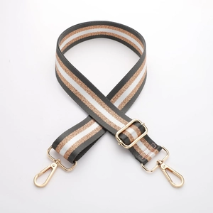 Detail of adjustable gray and white striped fabric bag strap with gold metal hooks