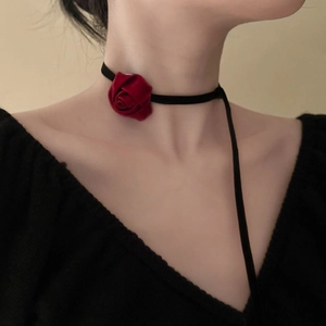 Detail of red velvet rose choker with long black fabric ribbons worn by a model