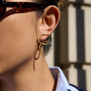 Irregular spiral gold titanium steel earrings shown on ear with a minimalist design