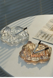 Detailed view of clear and amber iceberg glass ashtrays on a white desk setting