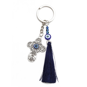 Detailed view of hollow silver cross keychain with evil eye bead and blue silk tassel