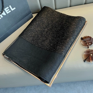 Detailed view of a black silk scarf with gold threads on a gold-rimmed tray