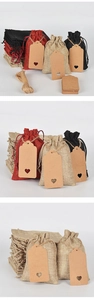 Detail view of linen drawstring gift bags in red, black, and natural with heart tags