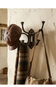 Detail showing vintage bronze cast iron coat rack with four hooks holding hat and scarf