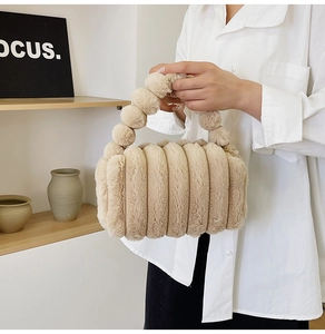 Fashionable beige plush handbag with ribbed texture and pom-pom handle detail