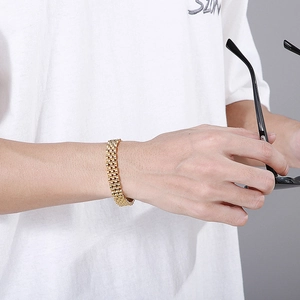 Detailed view of a gold stainless steel watch band bracelet worn on a male wrist