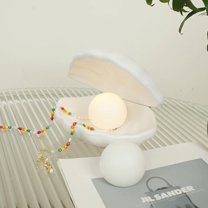 Detail of shell night light with glowing pearl and elegant bedside storage tray
