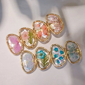 Elegant gold hair clips with dried flowers and iridescent shell flakes in resin