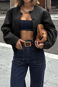 Close-up of black collarless vest jacket styled with blue denim corset and gold necklace