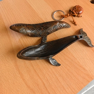 Detailed view of bronze whale incense burner featuring hollow wave patterns and lucky charm