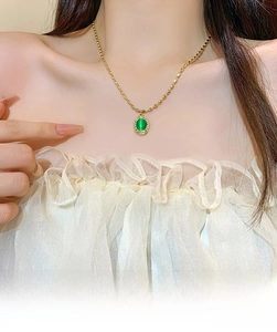Detail of vintage gold necklace with green cat-eye stone pendant on model neck