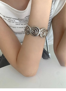 Close-up of a silver spiral cuff bracelet worn on wrist with polished metallic texture