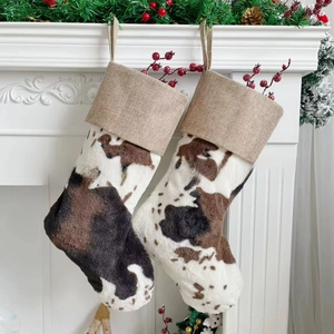 Detail of plush cow print Christmas stockings with rustic burlap cuffs on a fireplace