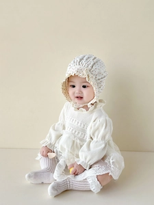Detailansicht der Babyhaube mit braunen Punkten und feiner Spitzenstickerei am Kleid