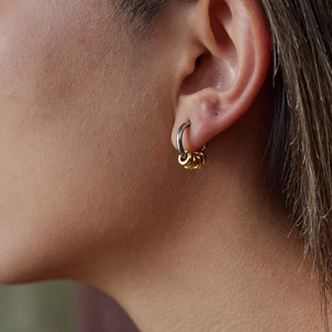 Close-up of two-tone stainless steel C-shaped hoop earrings worn on a model ear
