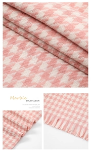 Macro detail of pink and white houndstooth knit scarf texture with fringe tassels