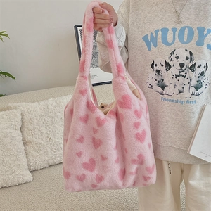 Detailed close-up of a pink plush tote bag with heart patterns held by a model