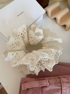 Détail d'un chouchou en dentelle blanche à double couche avec broderie ajourée fine
