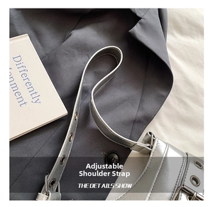 Close-up of silver mirror shoulder bag featuring an adjustable strap with metal eyelets